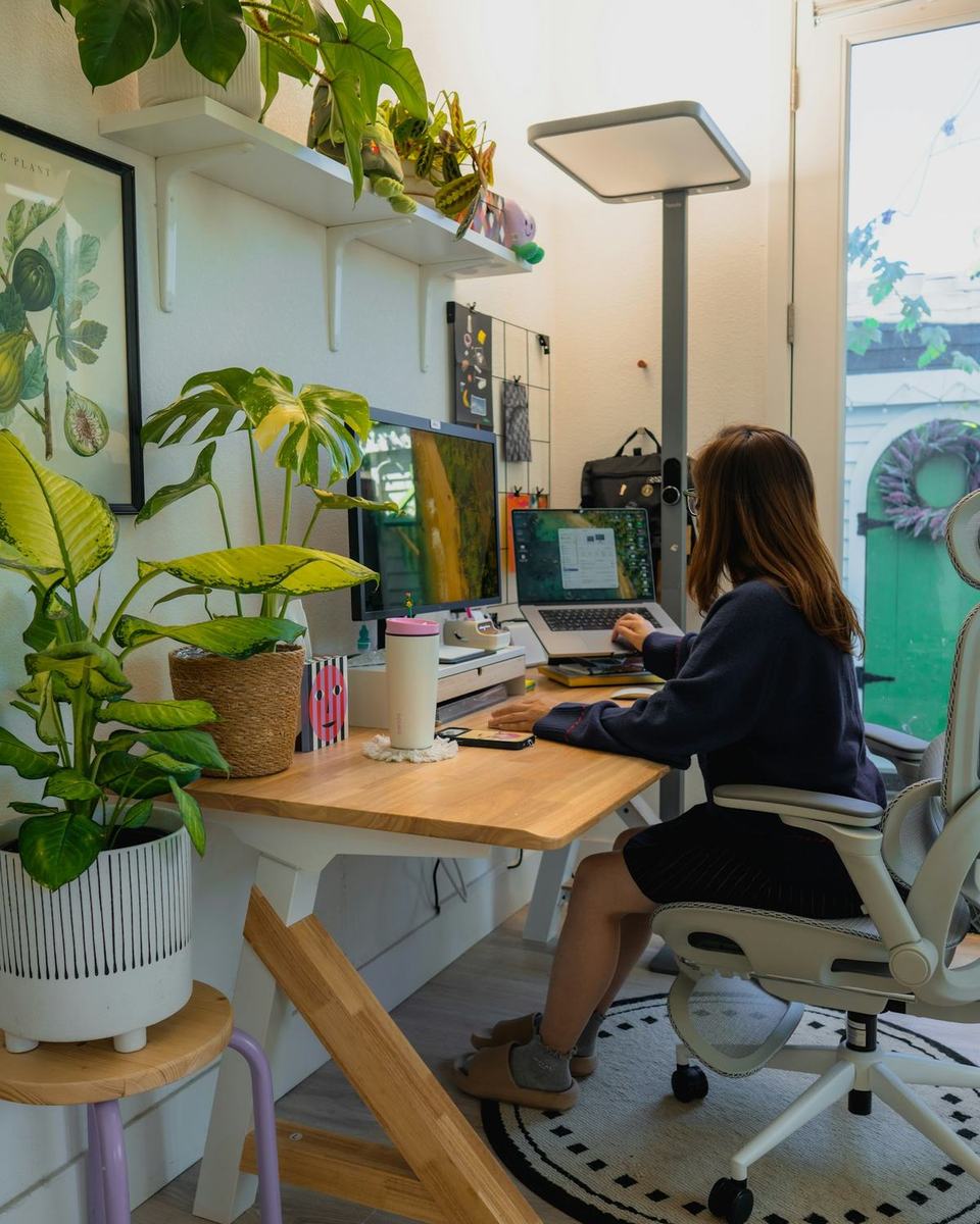 A person working at a tidy desk with plants and a computer
